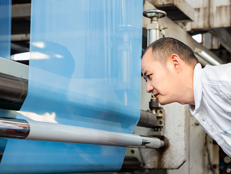 worker watching the glues being applied on the film